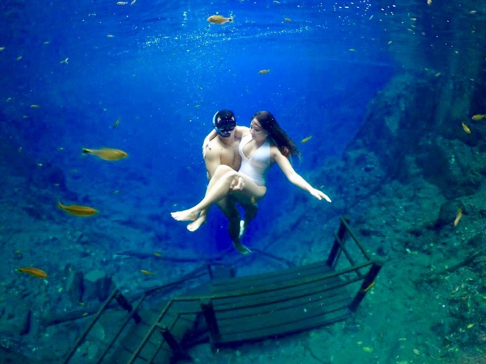 Casal utiliza escada da Lagoa Misteriosa durante mergulho — Foto: Redes Sociais