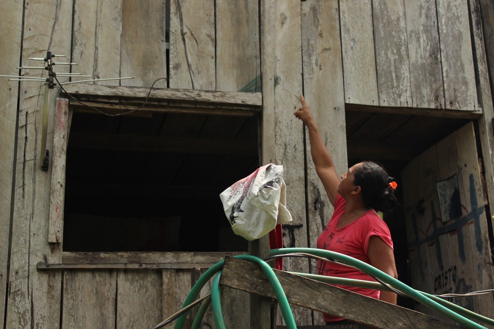 A agricultora Cesária Oliveira, mostra onde água do Rio Madeira chegou na cheia histórica de 2014 em Porto Velho.  — Foto: Pedro Bentes/G1