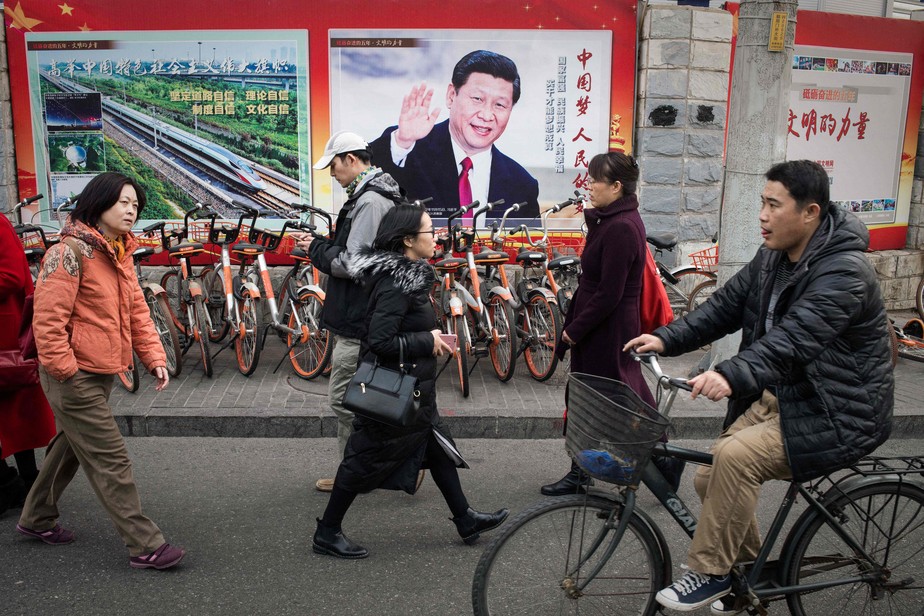 Pessoas caminham diante de cartaz mostrando o presidente chinês, Xi Jinping, em Pequim