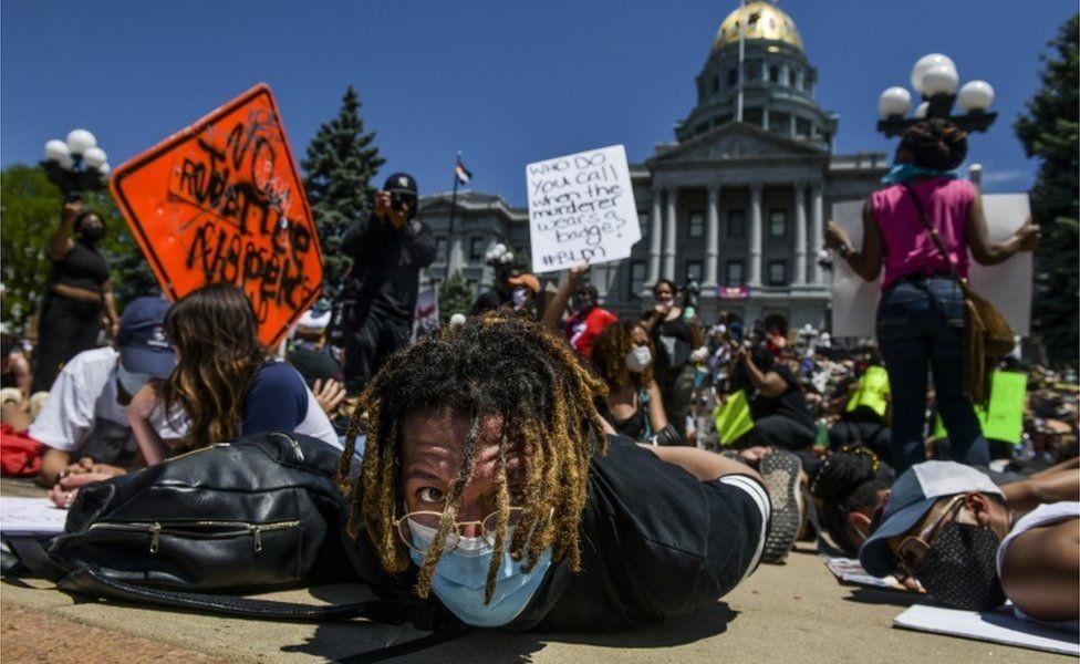 Multidão participa de de uma manifestação ao lado do Capitólio de Denver, no Estado do Colorado com as mãos atadas nas costas  (Foto: Getty Images via BBC)