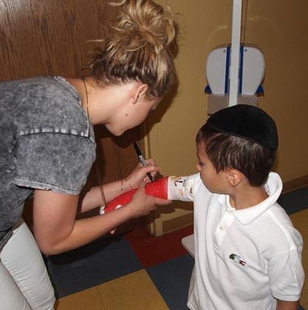 Jennifer Lawrence assinando gesso de menino (Foto: Facebook)