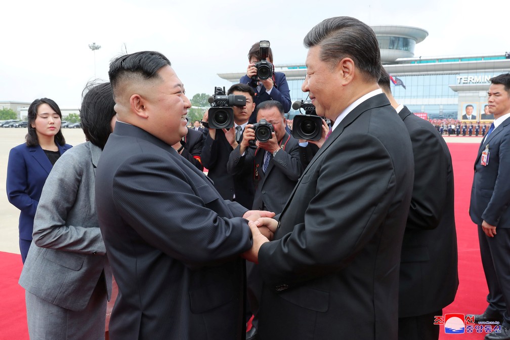 Kim Jong-un e Xi Jinping se cumprimentam no aeroporto de Pyongyang, na Coreia do Norte — Foto: KCNA via Reuters