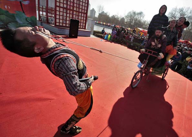 Em 2010, o chinês Yang Guanghe puxou um triciclo carregado com cinco pessoas com ganchos presos em suas pálpebras inferiores durante apresentação em Pequim (Foto: Christina Hu/Reuters)