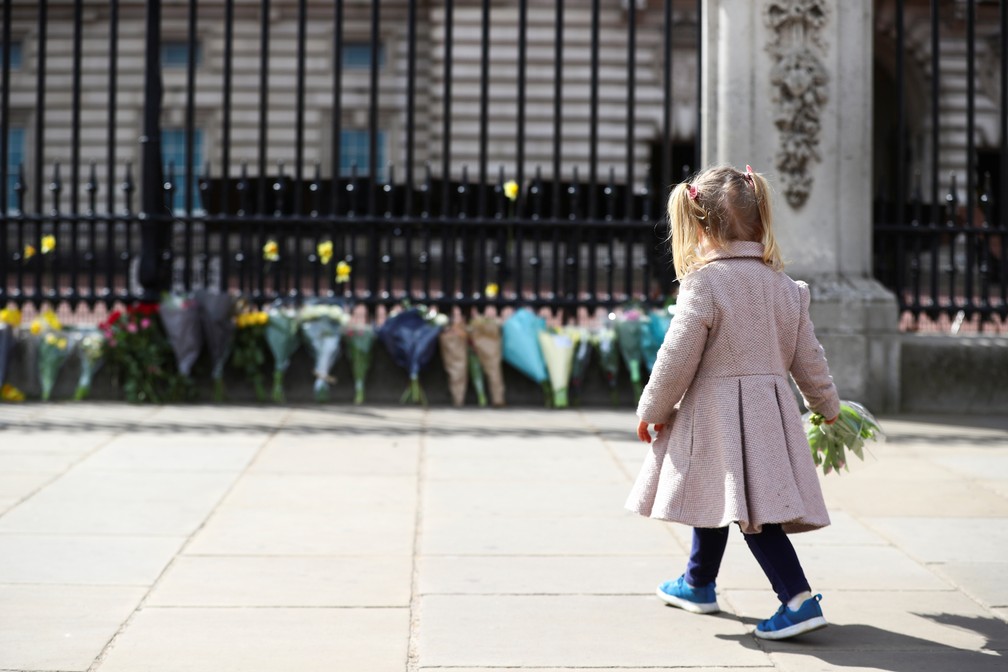 Maggie, de 2 anos, deposita um buquê de flores em frente ao Palácio de Buckingham em homenagem ao príncipe Philip, marido da Rainha Elizabeth II, em 9 de abril de 2021 — Foto: Hannah McKay/Reuters