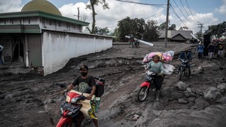 Pessoas resgatam pertences após erupção vulcânica do Monte Semeru, na vila de Kajar Kuning, em Lumajang, Indonésia — Foto: JUNI KRISWANTO/AFP
