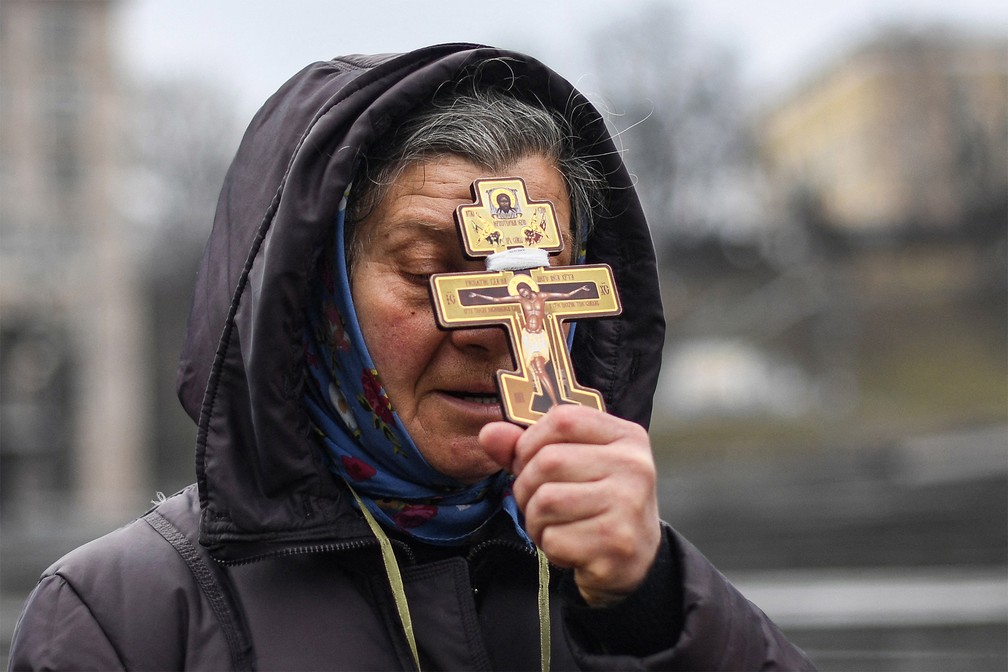 Uma religiosa segura uma cruz enquanto reza na Praça da Independência em Kiev, na manhã de 24 de fevereiro de 2022 — Foto: Daniel Leal/AFP