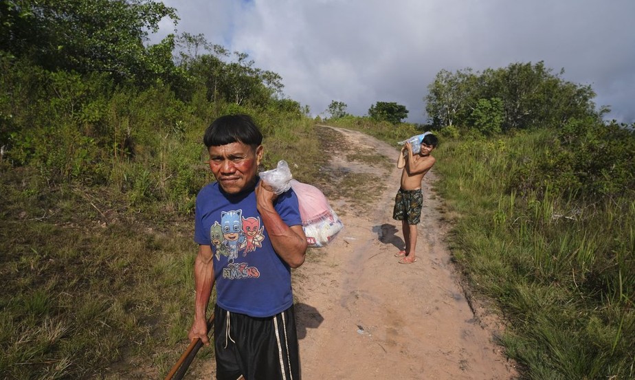 Indígenas Yanomami carregam água e alimentos para aldeia