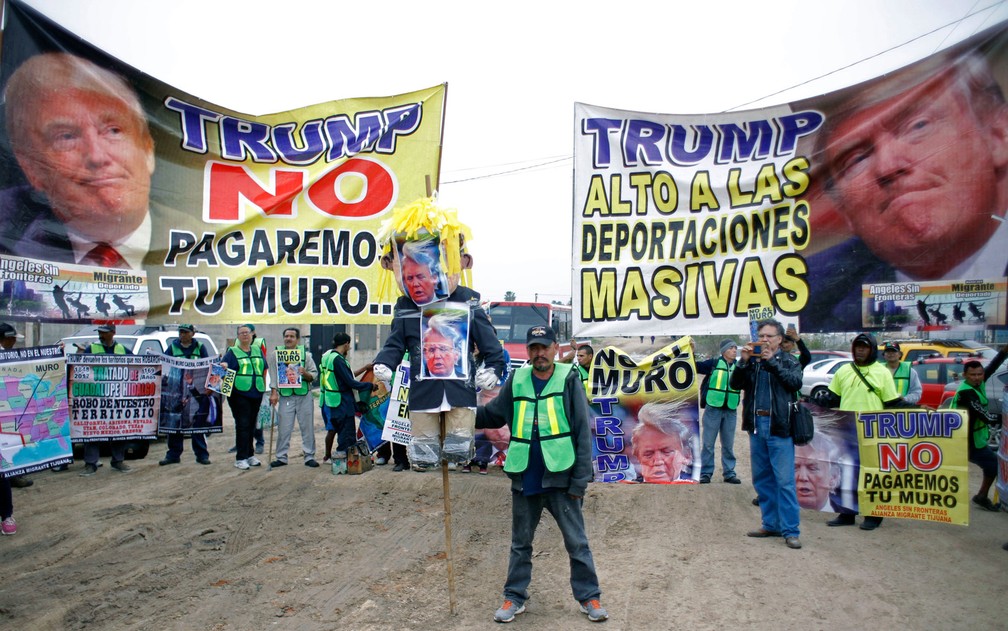 Manifestantes protestam do lado mexicano da fronteira, em Tijuana, contra a visita de Donald Trump a San Diego, na Califórnia, na terça-feira (13) (Foto: Guillermo Arias/AFP)