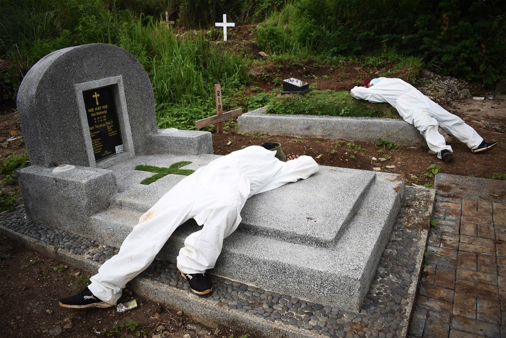 15 de junho - Exaustos, coveiros com roupas de proteção contra Covid descansam sobre túmulos de um cemitério em Bandung, na Indonésia, enquanto as mortes pela doença subiam bastante no país — Foto: Timur Matahari/AFP