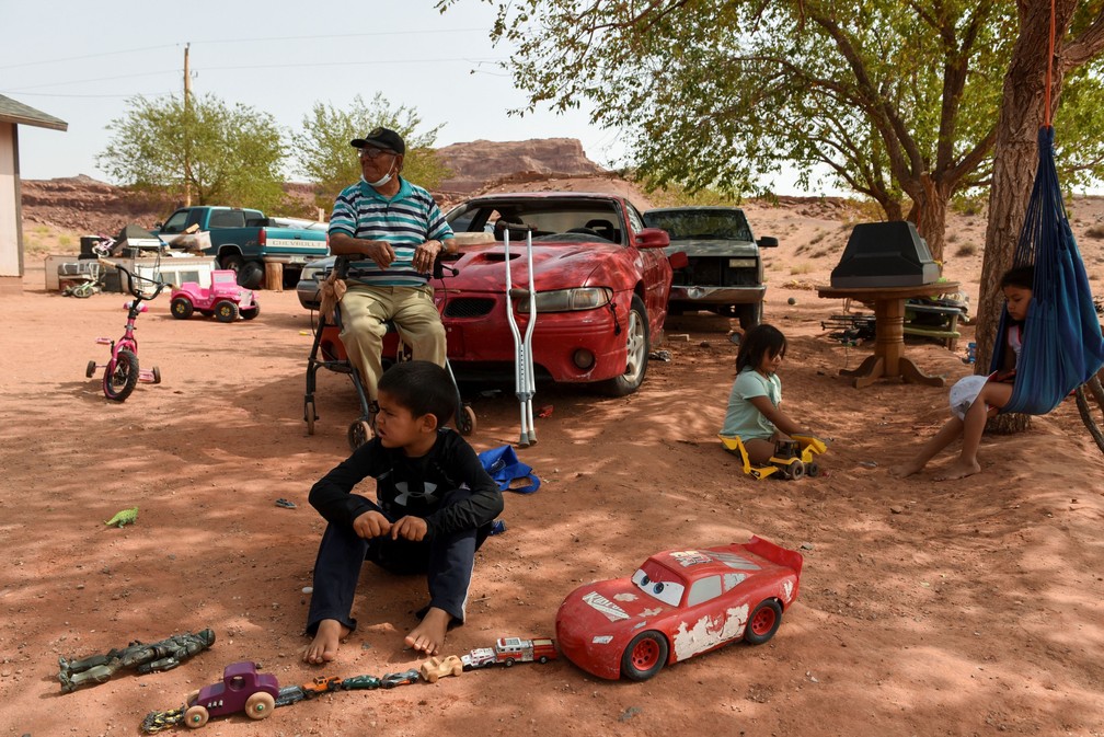 Evans John, de 87 anos, é visto com seus três netos Calais Chee, de 5, Aveya Chee, de 4, e Makaia Chee, de 8 anos, do lado de fora de sua casa no Bodaway Chapter perto de Gap, no Arizona, EUA — Foto: Stephanie Keith/Reuters