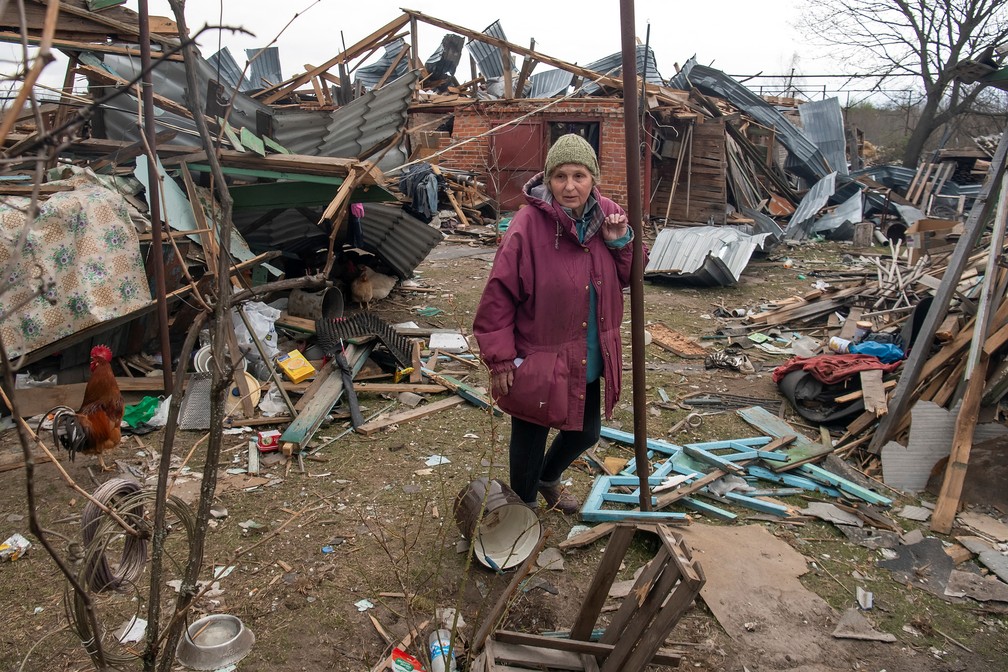 Foto mostra mulher em meio aos restos de sua casa em Kukhari, na região de Kiev, na Ucrânia, neste sábado (16). — Foto: Vladyslav Musiienko/Reuters