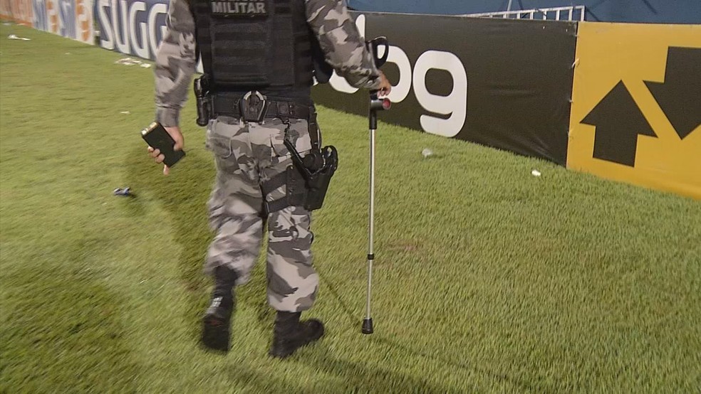Policial militar retira a muleta arremessada no gramado do estádio azulino — Foto: Reprodução/TV Liberal