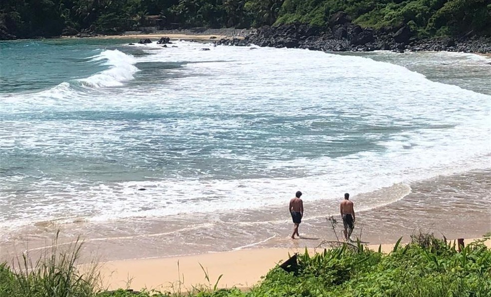 Dois homens caminharam na Praia do Meio, em Fernando de Noronha, apesar do decreto estadual de fechamento das praias — Foto: Luciana Schroden/Acervo pessoal 