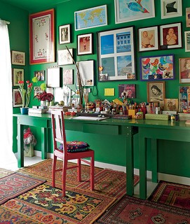 O escritório do diretor de arte e de cinema Thiago Bastos tem paredes verde-esmeralda com muitos quadros. No chão, uma composição de tapetes pequenos aquece o ambiente 
