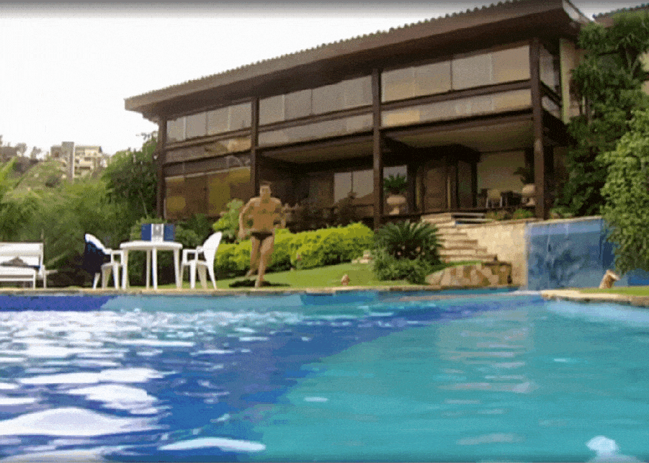 Danilo saltando na piscina com a casa ao fundo em Laços de Família