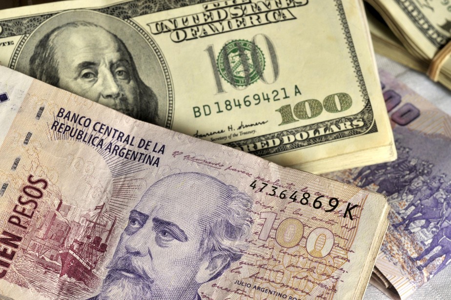 Pilhas de notas de 100 pesos argentinos e notas de 100 dólares americano
