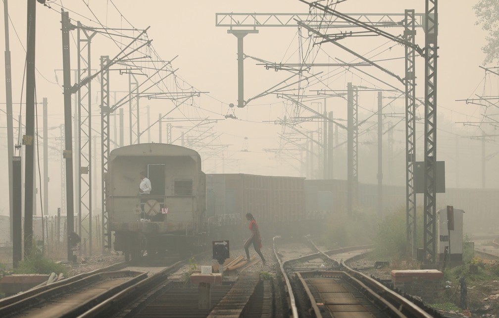 Mulher cruza linha do trem em Nova Délhi em meio a poluição em 12 de novembro de 2021 — Foto: Anushree Fadnavis/Reuters