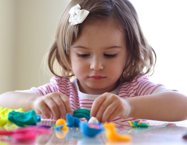 Criança brincando de massinha na mesa (Foto: Shutterstock)