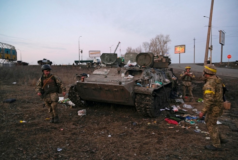 Militares ucranianos são vistos ao lado de um tanque destruído, que segundo eles pertencia a combatentes russos, perto de Kharkiv, na Ucrânia — Foto: Maksim Levin/Reuters