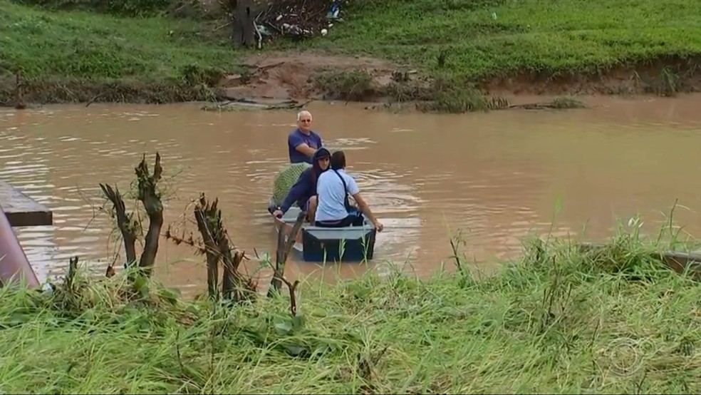 Morador está ajudando a fazer a travessia de ribeirão com barco após ponte de bairro ser levada durante temporal em Laranjal Paulista — Foto: TV TEM/Reprodução