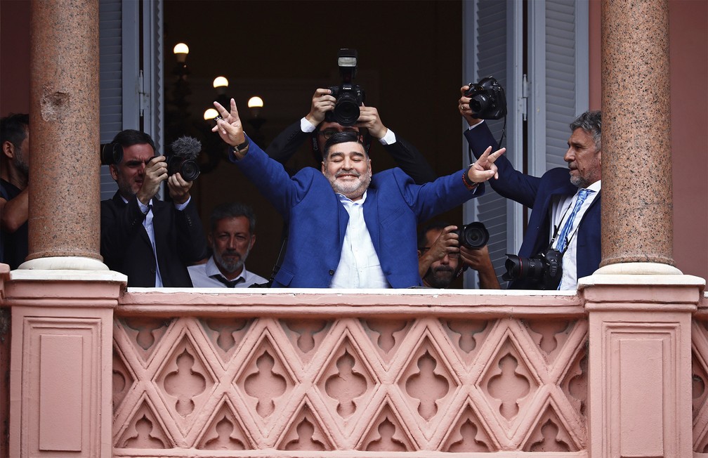 Diego Maradona acena para o público fazendo sinais da vitória de uma sacada da Casa Rosada, sede do governo argentino em Buenos Aires, após conversa com o presidente Alberto Fernandez em dezembro de 2019 — Foto: Marcos Brindicci/AP/Arquivo