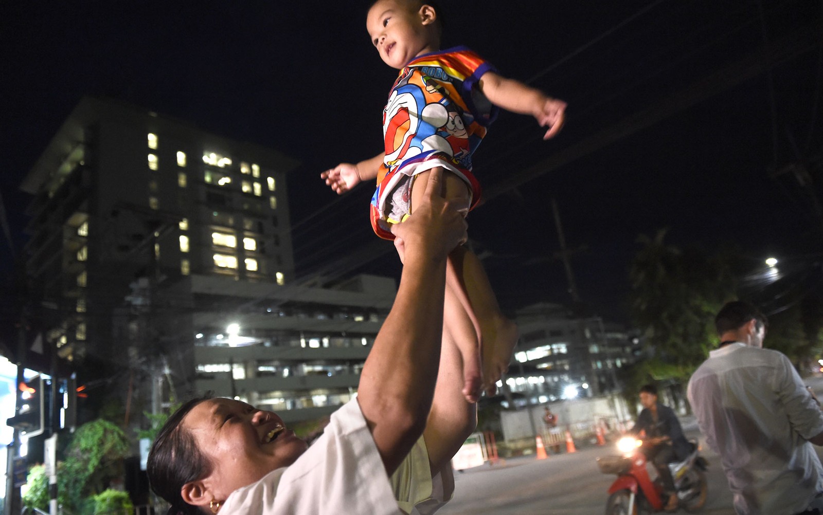 Uma mulher ergue seu bebê ao comemorar a chegada das ambulâncias transportando os últimos resgatados na caverna Tham Lang ao hospital em Chiang Rai, na terça-feira (10) (Foto: Lillian Suwanrumpha/AFP)