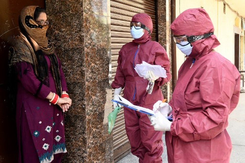 Equipe médica visita indianos em área residencial em Amritsar, na Índia, neste domingo (12) — Foto: NARINDER NANU / AFP