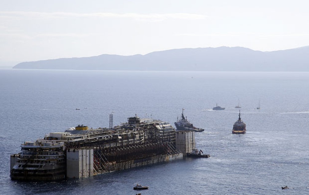 O navio Costa Concordia é rebocado da Ilha de Giglio em 2012, mais de 2 anos após naufrágio que matou 32 pessoas na costa da Itália — Foto: Gregorio Borgia/AP