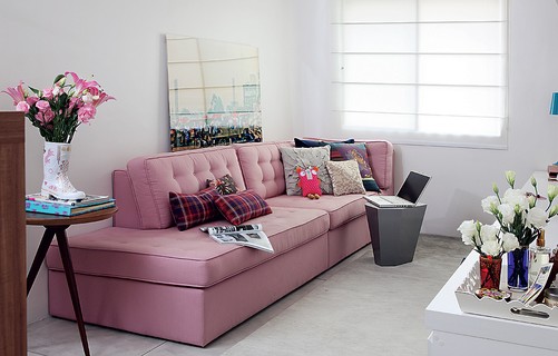 Na sala projetada pelo escritório Arquitetura Paralela, o sofá rosa é o destaque. Sem braços, ainda vira cama para hóspedes
