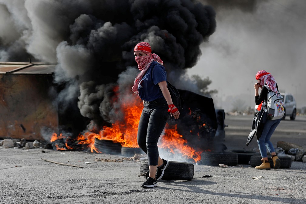 Manifestante palestina é vista na frente de pneus queimados durante um protesto anti-Israel perto do assentamento judeu de Beit El na Cisjordânia ocupada por Israel neste sábado (16) — Foto: Mohamad Torokman/Reuters