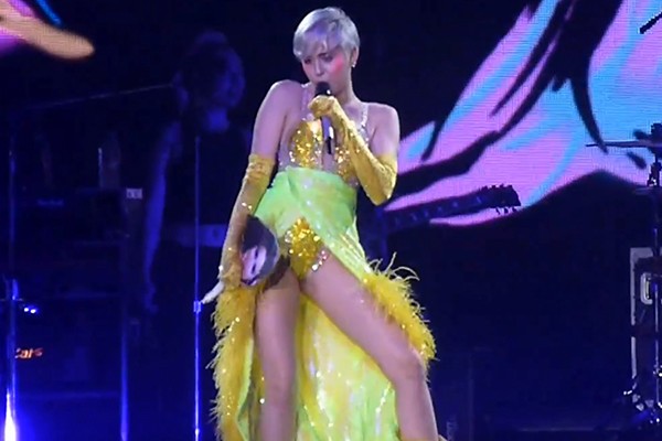 Miley Cyrus com imagem de Selena Gomez jogada ao palco (Foto: Reprodução Youtube)