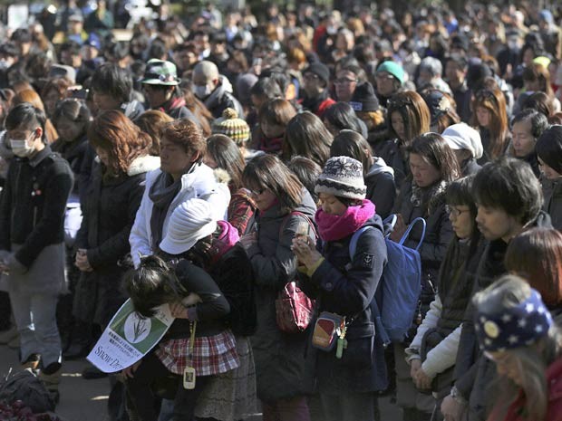 Japoneses fazem silêncio durante 1 minuto, a partir das 2h46 desta terça-feira (11), em Tóquio, em memória dos cerca de 19 mil mortos e desaparecidos após o potente terremoto e devastador tsunami que varreram o nordeste do Japão há 3 anos.  (Foto: Eugene Hoshiko / AP Photo)