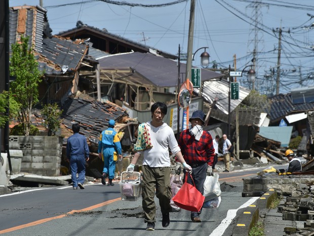Moradores tentam retirar objetos de suas casas destruídas após terremoto em Mashiki (Kumamoto), neste domingo (17).  (Foto: AFP)