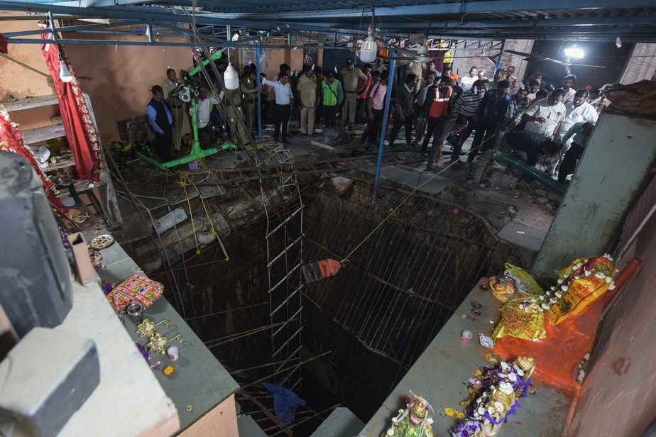 Equipes de resgate em torno do perímetro da área do piso desmoronado que cobria um poço onde pessoas caíram num templo hindu na Índia em 30 de março de 2023