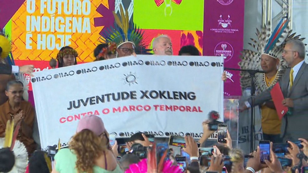 No acampamento Terra Livre, Lula levanta faixa contra marco temporal — Foto: TV Globo/Reprodução