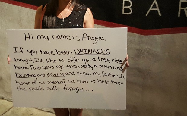 Angela Canzani segura o cartaz em que oferece carona a jovens em bares em memória aos dois anos de morte do pai, em um acidente (Foto: Reprodução / Imgur)