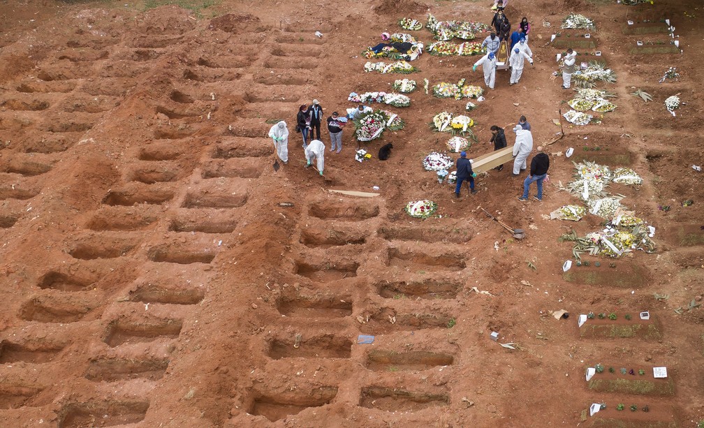 Funcionários em roupas de proteção enterram três vítimas do novo coronavírus no cemitério de Vila Formosa, em São Paulo. O Brasil está se aproxima de 2 milhões de casos de Covid-19 e 75 mil mortes — Foto: André Penner/AP