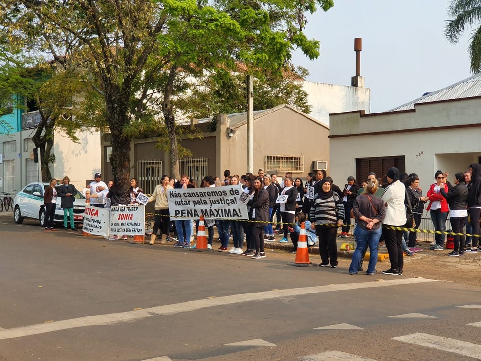 Pessoas estão reunidas em frente ao forum com cartazes pedindo justiça — Foto: Alfredo Pereira/RBS TV