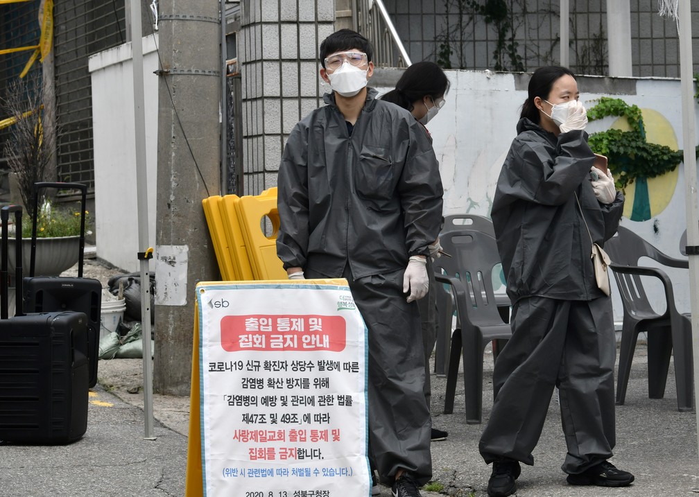 Funcionários do governo vestindo roupas de proteção são vistos em um posto de controle temporário para restringir o acesso à Igreja Sarang Jeil em Seul, na Coreia do Sul, nesta segunda-feira (17)  — Foto: Jung Yeon-Je/AFP