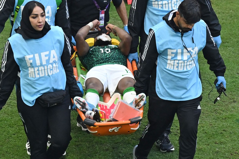 Al Shahrani deixa o campo de maca após ser atingido na cabeça pelo goleiro da Arábia Saudita — Foto: Glyn Kirk / AFP