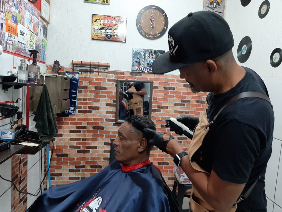 Em homenagem ao Dia dos Pais, que é comemorado no segundo domingo de agosto, o barbeiro oferece cortes de cabelo gratuitos na sua barbearia, em Cuiabá — Foto: Ariane Veiga/G1