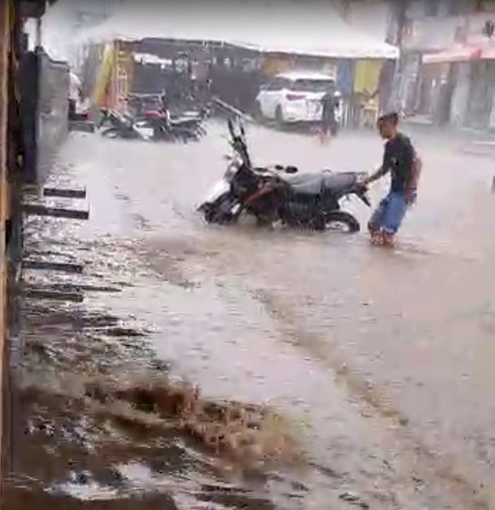 Morador tenta retirar motocicleta da rua já coberta pela água — Foto: Arquivo pessoal