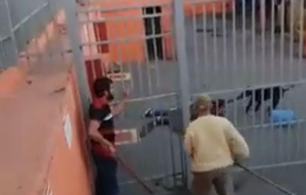 Imagem feita por populares mostra momento em que homem entrava em distribuidora para ajudar auxiliar administrativo atacada por pitbull — Foto: Reprodução