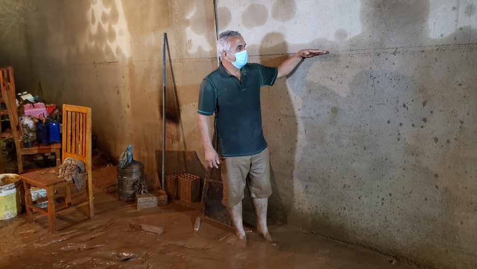 O corretor de imóveis aponta na parede de casa a marca deixada pela água do Rio Maracujá — Foto: Danilo Girundi/TV Globo
