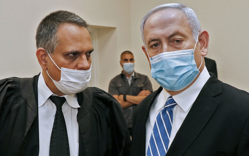 No primeiro dia do julgamento por corrupção, em maio, o primeiro-ministro de Israel, Benjamin Netanyahu (direita), usou máscara de proteção dentro da corte em Jerusalém; neste domingo (19), ele não compareceu à audiência — Foto:  Ronen Zvulun/Pool/AFP 