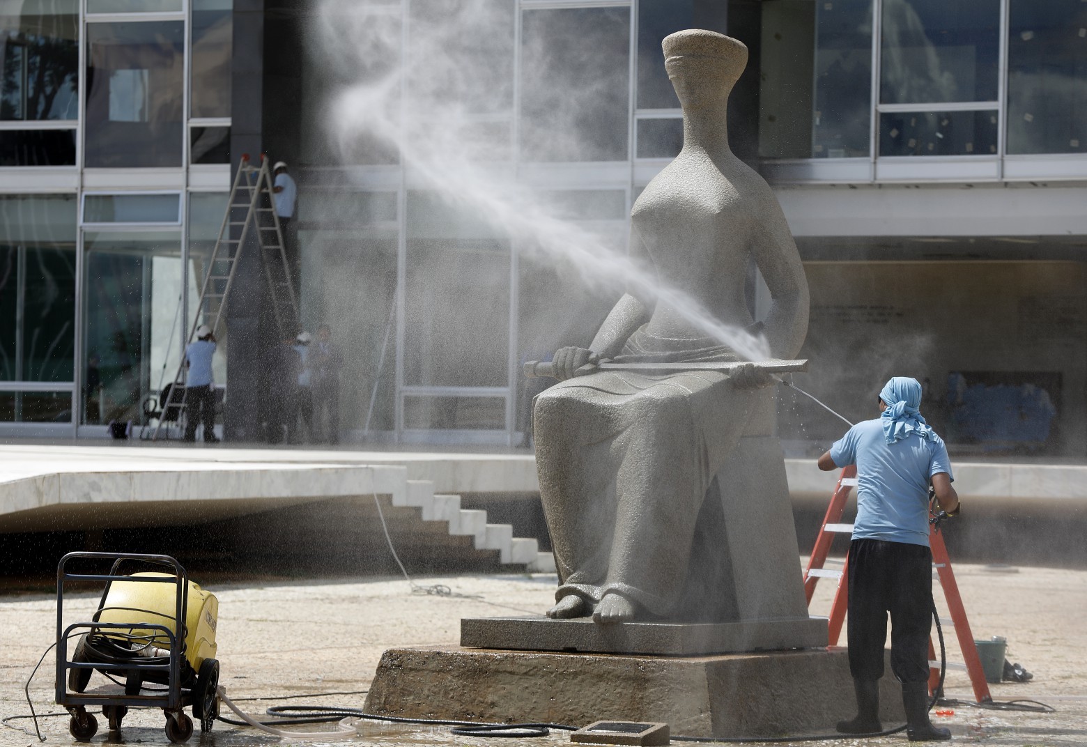 Funcionário da equipe de limpeza do STF limpa estátua que foi pichada por manifestantes  — Foto: Cristiano Mariz