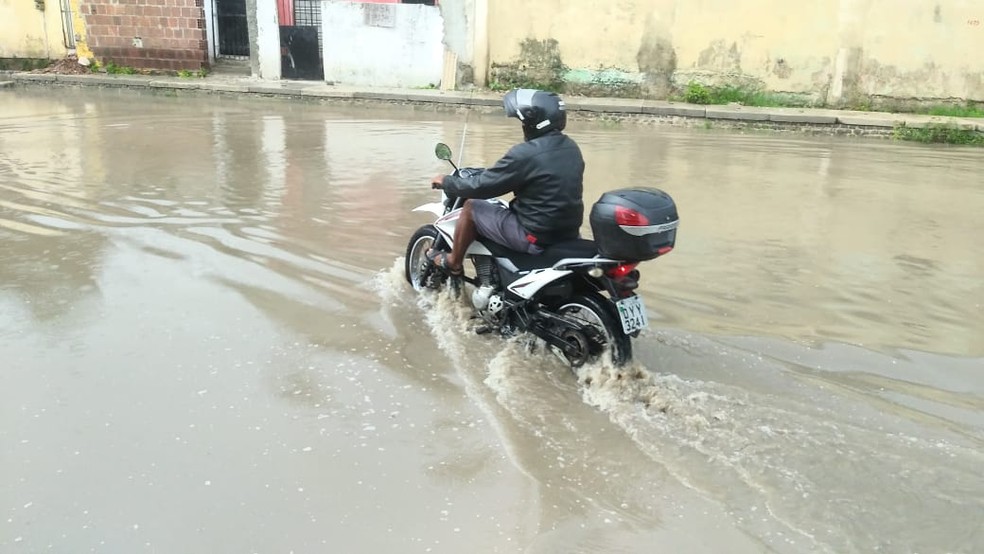 Motociclista passa pela água que alaga a Avenida Pedro Alves Cabral, em Jardim Atlântico, em Olinda, nesta quarta-feira (6) — Foto: Everaldo Silva/TV Globo