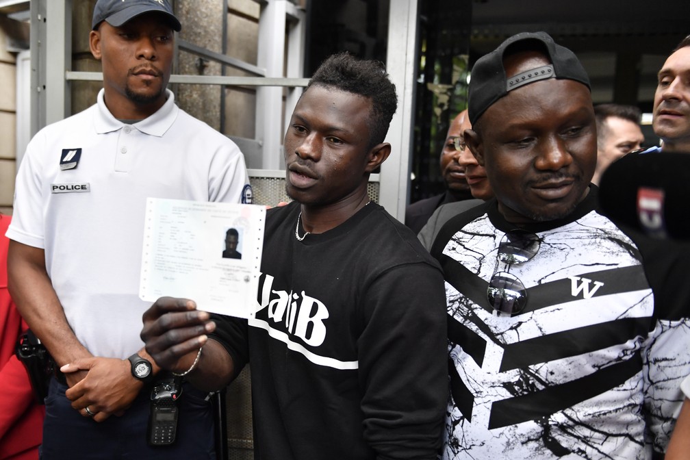 Imigrante malinês Mamoudou Gassama segura sua permissão temporária de residência após receber documento nesta terça-feira (29) em Bobigny, na França (Foto: Gerard Julien/AFP)