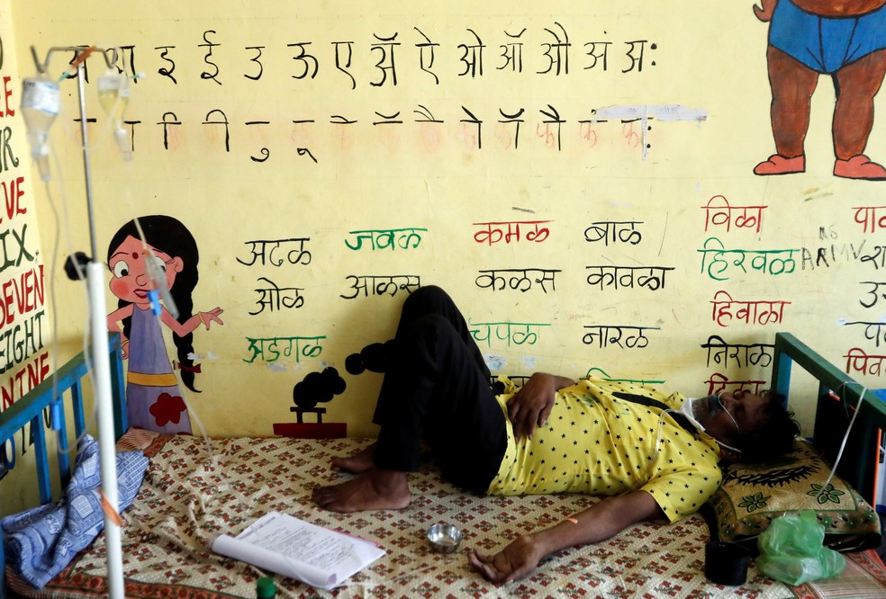 Paciente com Covid-19 recebe suporte de oxigênio enquanto dorme dentro de sala de aula transformada em hospital provisório nos arredores de Mumbai, na Índia, em 24 de maio — Foto: Francis Mascarenhas/Reuters