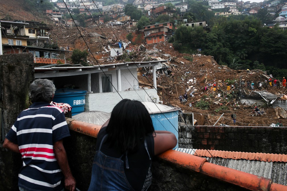 Moradores observam essoas trabalhando em local de deslizamento de terra em Petrópolis  — Foto: Ricardo Moraes/Reuters